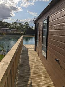 a wooden dock next to a house with a lake at Waterfoot Lodge in Little Habton
