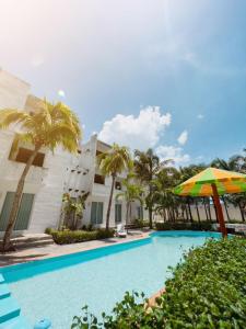 una piscina con sombrilla y un edificio en Paraíso Seyba Hotel, en Seybaplaya