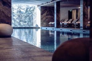 uma piscina de água com cadeiras num edifício em Antarès Méribel Resort & SPA em Les Allues