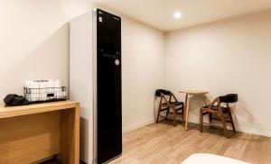 a black refrigerator in a room with two chairs at Hotel Laon in Tongyeong