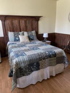 a bedroom with a bed with a quilt on it at Hôtel Sous la Croix 152725 in Tadoussac