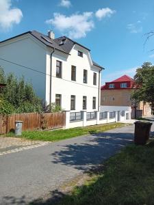 a white house with a fence on a street at Apartmány Šrámek Stříbro in Stříbro