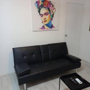 a black couch in a room with a painting at Condos Frida in Cozumel