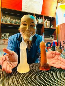 a man with a mask sitting at a table with bottles at Hostel THAY83 Miraflores Lima in Lima