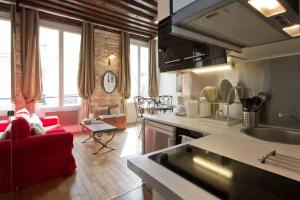 パリにあるAuthentic Apartment Maraisの赤いソファのあるキッチンとリビングルーム