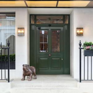 a bronze dog statue in front of a green door at Holmes Hotel London in London