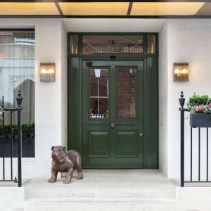 a bronze dog statue in front of a green door at Holmes Hotel London in London