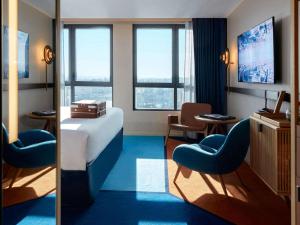 um quarto de hotel com uma cama, cadeiras e janelas em SO/ Paris Hotel em Paris