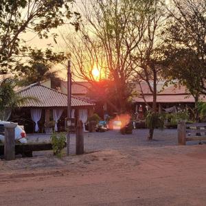 a sunset in front of a house with the sun setting at Pousada Cantinho de Casa in Nobres