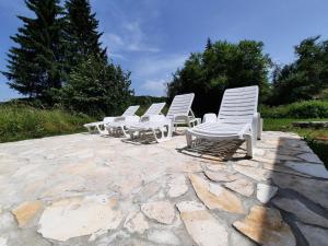 a row of white chairs sitting on a stone patio at Vacation House Home, Plitvice Lakes National Park in Plitvička Jezera