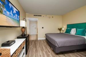 a hotel room with a bed and a flat screen tv at Ocean view Balcony Walk to beach PW722 in Honolulu