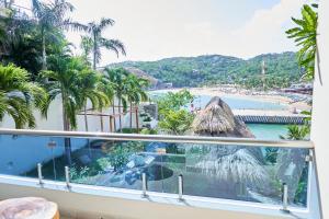 balcón con vistas a la playa y a las palmeras en Hotel Casa Justina en Puerto Ángel