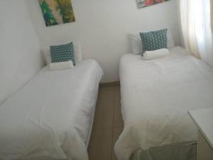 Duas camas num quarto com lençóis brancos e almofadas azuis em Manor house em Durban