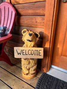 Ein Holzbär mit einem Schild, auf dem "Willkommen" steht. in der Unterkunft A Cozy Cabin Escape in Tijeras-Hot Tub-Game room-Pet Friendly! in Tijeras