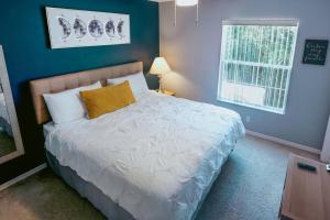 um quarto com uma cama branca e uma parede azul em Ultimate Vacation Villa Near Disney Townhouse em Kissimmee