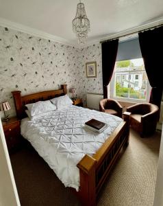 a bedroom with a bed and a chair and a window at Caer Menai in Caernarfon