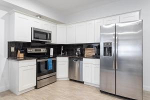 a kitchen with white cabinets and a stainless steel refrigerator at The Cherry Suites - Chinatown in Philadelphia