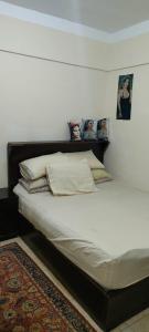 Una cama con sábanas blancas y almohadas en un dormitorio en الساحل الشمالي, en El Alamein