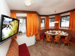 a dining room with a table and a flat screen tv at Zirmblick in Saalbach-Hinterglemm