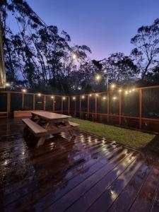 a picnic table on a deck at night with lights at Blue Mountains Sweet Retreat in Leura