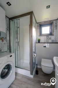 uma casa de banho com uma máquina de lavar roupa e um WC em Euforia Górzno - nowoczesne, klimatyzowane domki z jacuzzi i sauną em Górzno