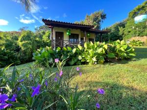una pequeña casa en un jardín con flores púrpuras en Pousada Simpatia da Ilha, en Fernando de Noronha