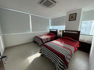 2 camas sentadas en una habitación con azulejos blancos en Departamento en Manta Edificio Poseidon, en Manta