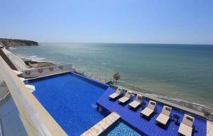 a swimming pool with chairs and the ocean at Departamento en Manta Edificio Poseidon in Manta