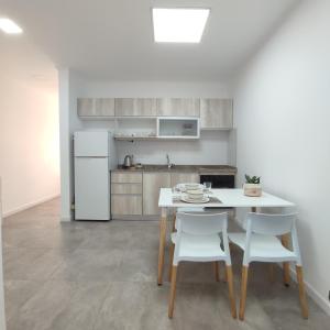 Villa Sarita 3D في بوساداس: مطبخ مع طاولة وكراسي وثلاجة بيضاء
