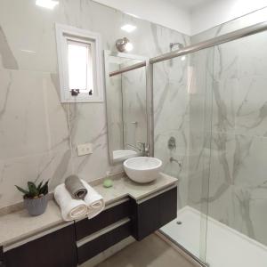 y baño blanco con lavabo y ducha. en Villa Sarita 3D en Posadas