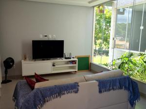 uma sala de estar com um sofá branco e uma televisão de ecrã plano em Casa de praia em Sauipe em Porto de Sauípe