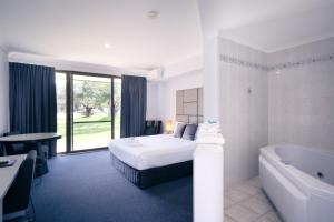 Habitación de hotel con cama y bañera en Island Palms Motor Inn en Forster