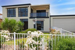 ein weißer Zaun vor einem Haus in der Unterkunft Beachfront Bliss- Aldinga Beach House - 5 BR in Aldinga Beach