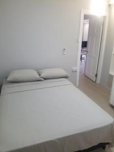 - un lit blanc dans une chambre blanche dotée d'un couloir dans l'établissement Classical accommodation, à Calliste Land Settlement