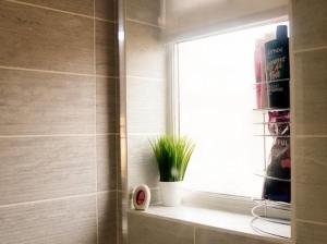 a window in a bathroom with a plant on a shelf at Home in Speke- 8 mins walk to airport in Speke