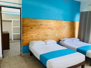 two beds in a room with blue walls and a mirror at Hotel Lu Acapulco in Acapulco