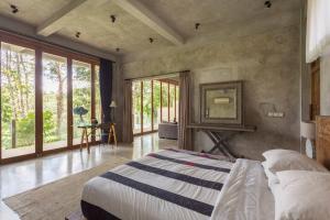 a bedroom with a bed in a room with windows at RiverView Gardens in Ubud