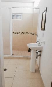 La salle de bains blanche est pourvue d'un lavabo et d'une douche. dans l'établissement Hotel Lu Acapulco, à Acapulco