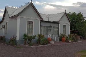 una casa blanca con plantas delante en La Casona, chalet rural en finca con piscina JUNÍN DE MENDOZA en Junín