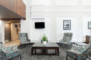 a lobby with chairs and a table and a tv at Sandman Hotel Red Deer in Red Deer