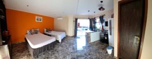 Zimmer mit 2 Betten und einer orangefarbenen Wand in der Unterkunft Recanto dos Coelho - Buzios in Búzios