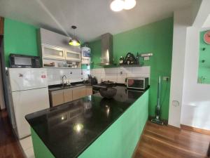 uma cozinha verde e branca com um balcão preto em Acogedor y Luminoso 2 Ambientes Centro Morón em Morón