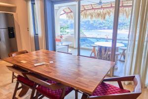 a dining room table with chairs and a large window at Hotel Casa Justina in Puerto Ángel