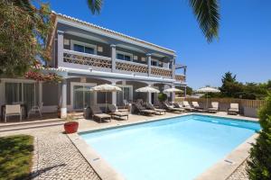 a villa with a swimming pool in front of a house at Costa d'Oiro Ambiance Village in Lagos