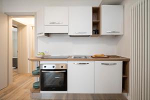 a kitchen with white cabinets and a stove at SnowLake Suite & Apartment in Alleghe