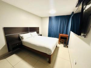 a bedroom with a bed and a chair and a television at OQ MIRADOR CLASSIC - AIRPORT in Arequipa