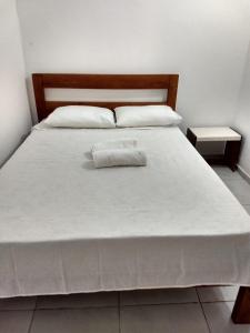 Una cama blanca con dos almohadas encima. en Hospedagem Brisa e Mar en Rio do Amaro