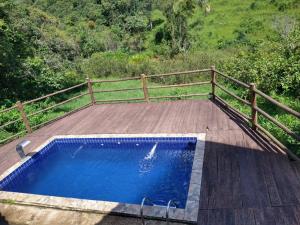 a swimming pool on a wooden deck next to a fence at Solar dos Vilela in Vargem Bonita