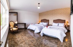 una habitación de hotel con 3 camas y una silla en CASA LOMA HOTEL BOUTIQUE & TERRAZA GASTRO, en Popayán