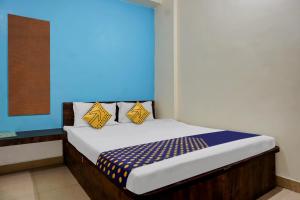 a bed with yellow and blue pillows in a room at SPOT ON Samadhan Lodge in Pune